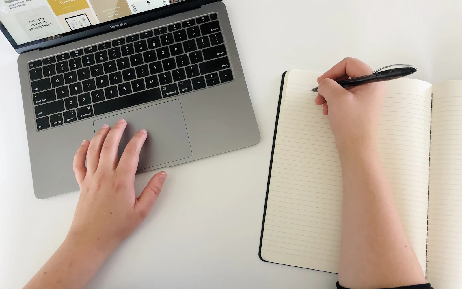 Person using a laptop and writing notes